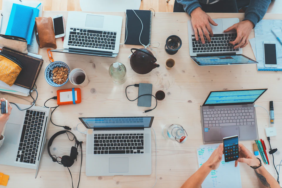 Team working together on laptops and phones around a table